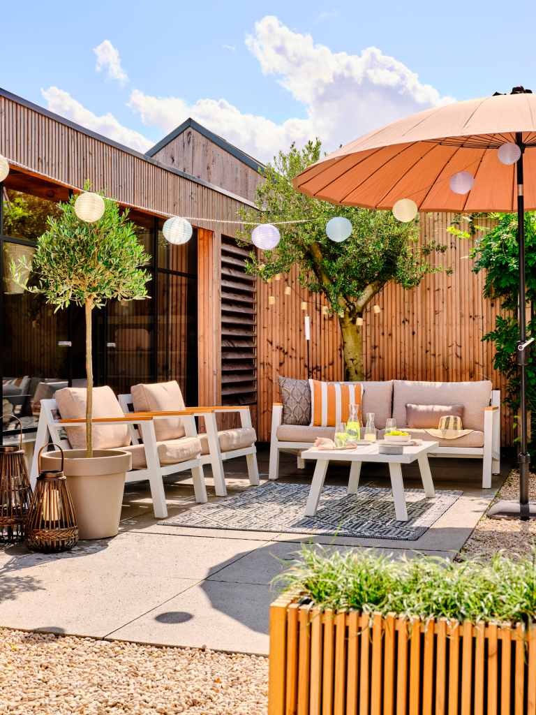 Gezellige tuin met witte houten tuinset en oranje parasol